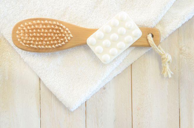 Care tools for a perfect skin before the bath including a dry brush, a masseur with capitons and a white towel