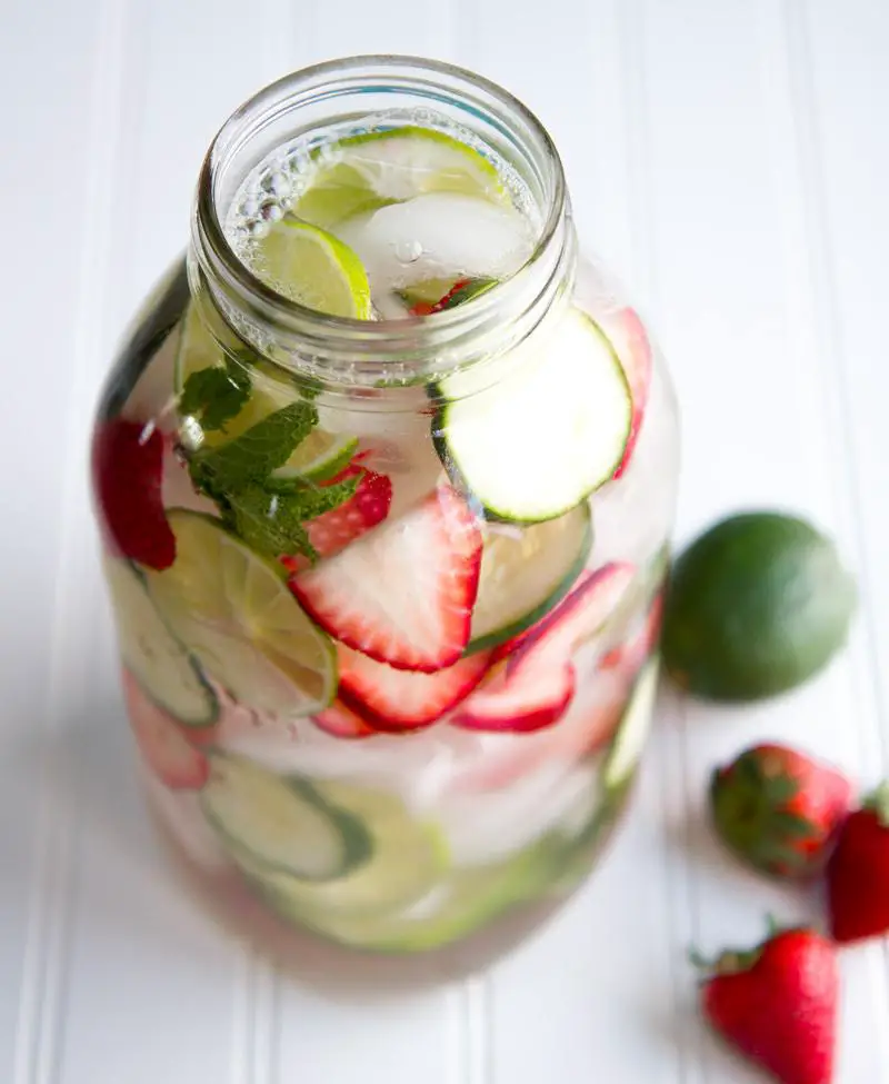 Mason pot full of fruit infused water with strawberry, cucumber, lemon and mint.