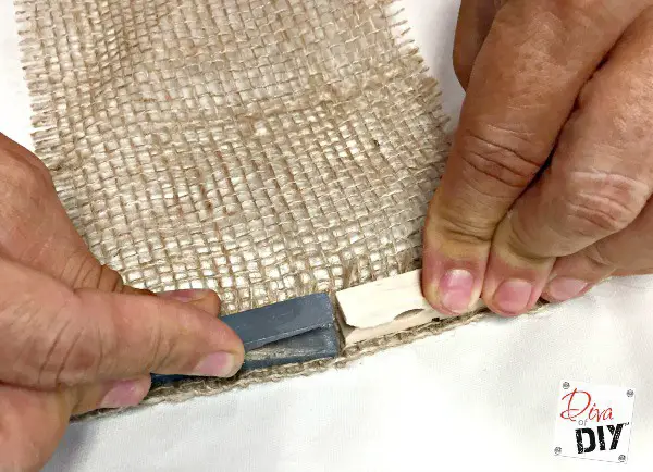 Place a strip of hot glue one inch from one of the ends of the burlap strip