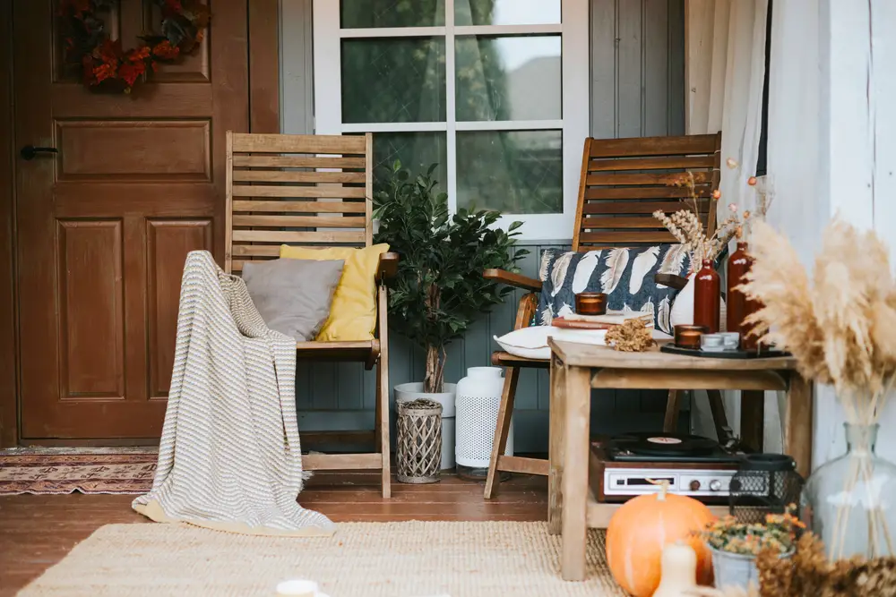 A cozy backyard for fall with a wooden chair and a pumpkin on the porch.