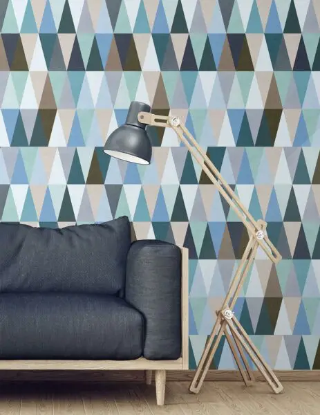 A living room with a blue couch and blue triangle wallpaper that perfectly captures teenage individuality.